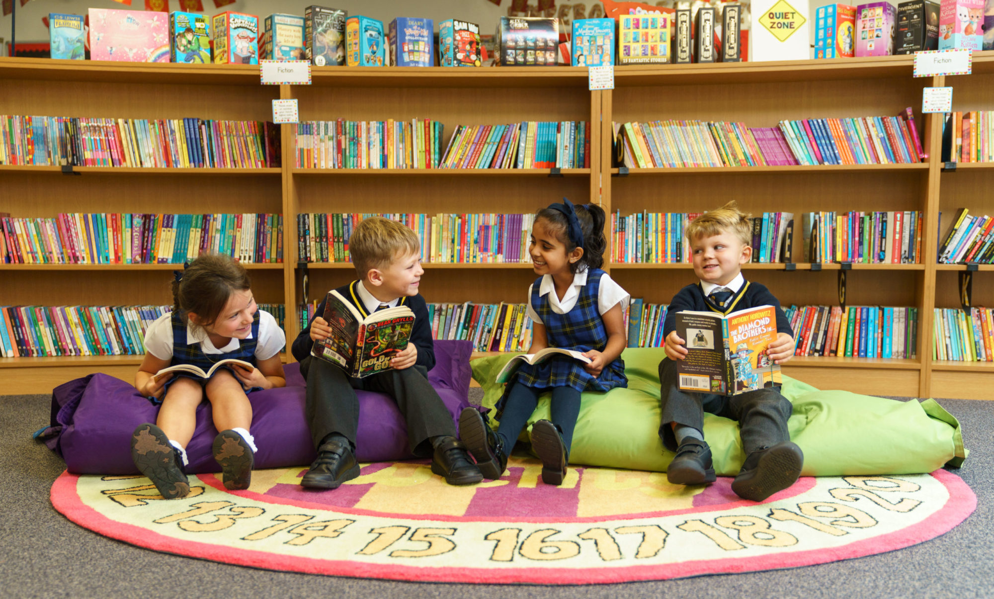 Four reception-age students of Ratcliffe College sat on beanbags, reading books and smiling